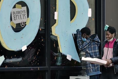 A group passes by a sign in the window of Busboys & Poets in Ward 8 in Anacostia, in Washington, DC.