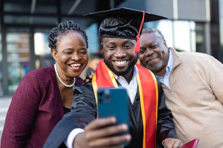 A college graduate taking a photo with his parents.