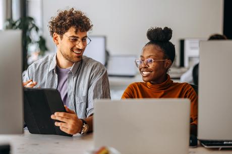 Two people in front of desktop computers.
