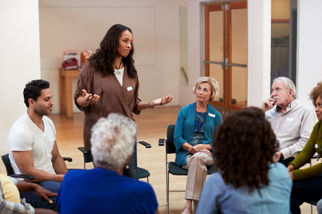 A woman stands to speak at a group therapy session.