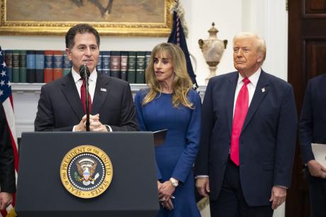 President Donald Trump and Susan Dell look on as Michael Dell speaks at a podium in the White House. 