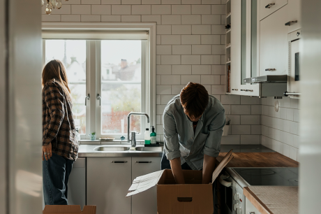 A couple unpacks boxes in a kitchen