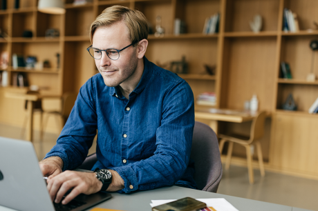 A man sits and types at a laptop