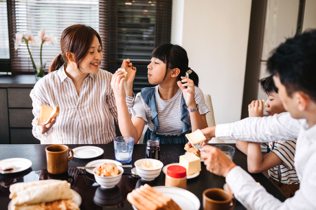    A group of four people sit around a bright dining table sharing a meal.