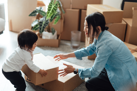 Photo of a toddler helping her mother pack a box.