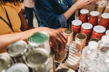 Photo of volunteers stacking items on a shelf at a food pantry.