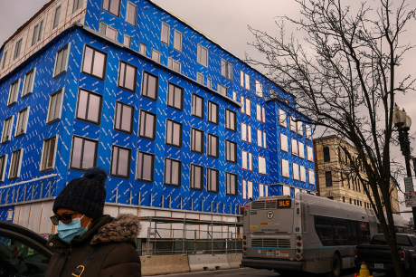 Photo of a pedestrian walking by a mixed-income housing project in Boston.