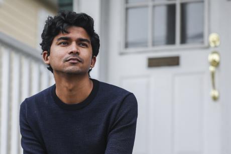 Young man poses in front of his home