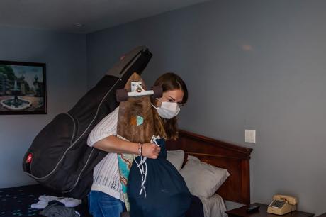 Person experiencing homelessness packs their bags in a hotel