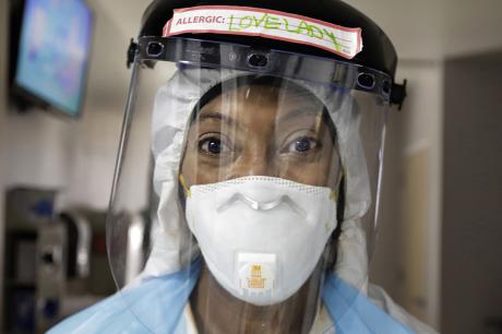 A nurse stares at the camera wearing a mask and face shield 