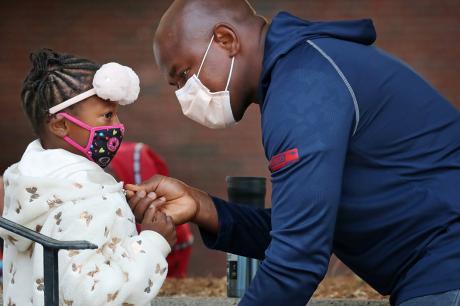 A father helps his daughter with her jacket while dropping her off for her first day of 1st grade at the Lincoln-Hancock Community School in Quincy, MA on September 17, 2020.