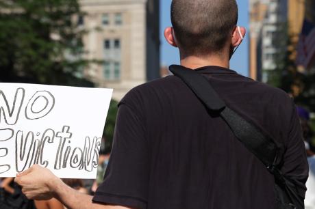 Protester holds a sign that says "no evictions"