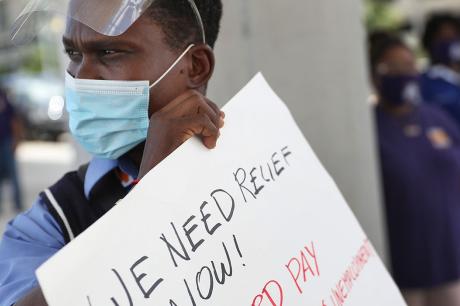 Protester holds a sign that reads, "we need relief now!"