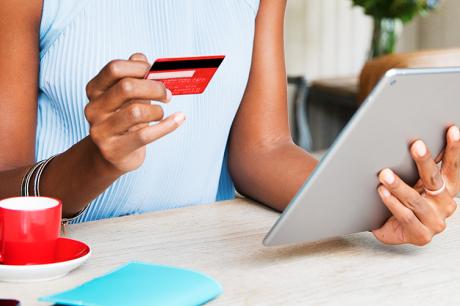 Person looks at credit card and tablet
