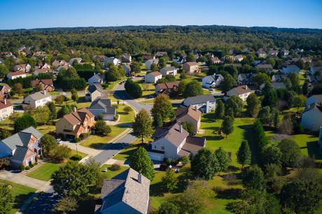 person at a desk writing in a noteook next to a laptop