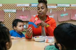 A woman crafting with young children in a classroom.