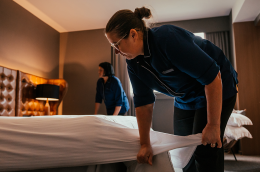 A hotel worker making a bed. 