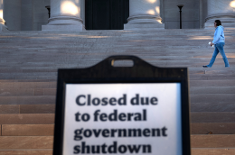 A woman walks past a sign indicating the National Gallery of Art is closed during the government shutdown