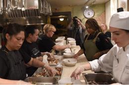 Restaurant workers gather around a table and plate food