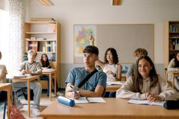 Girls and boys learning while sitting at desk in classroom 