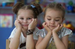 Two children hold their heads in their hands, one looks at the camera