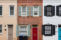 A row of brick historic row houses with stoops and traditional windows along a residential street in Washington, D.C