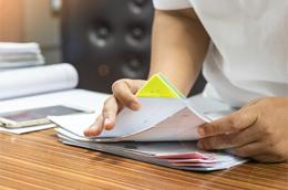 a photo of teacher searching for documents of desk