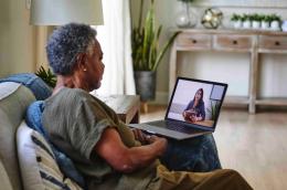 Photo of an older Black woman on a video call with a health care provider.
