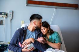 Parents embracing their newborn in a hospital room.