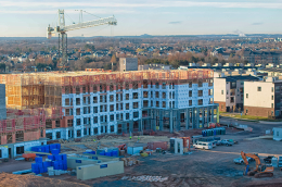 An aerial view of a large building under constriction in front of a gravel construciton site