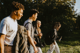 photo of happy male and female friends walking on road in park