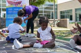 Four toddlers play with chalk outside