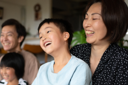 Family laughing together at home, showing joy and closeness in a warm, cozy setting.