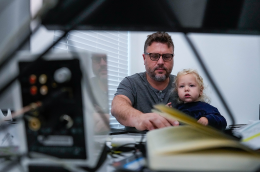 A man holds a child on his lap while he uses a computer