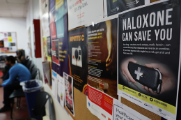 A sign for Naloxone hangs on a wall as students learn to put together a Naloxone spray gun in a class on opioid overdose prevention held by non-profit Positive Health Project on August 9, 2017 in New York City