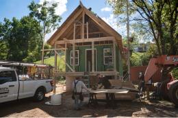 Workers constructing a small house during framing and exterior installation.