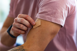 An adult placing a nicotine patch on their arm.