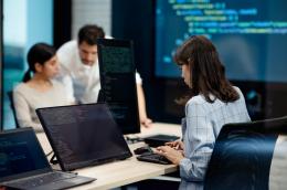 People working at computers with coding screens.