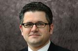 A photo of Mark Calabria. Slight smile, suit, dark hair, glasses.