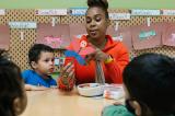 A woman crafting with young children in a classroom.