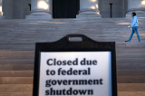 A woman walks past a sign indicating the National Gallery of Art is closed during the government shutdown