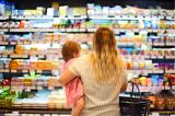 photo of woman standing holding child in front of grocery aisle