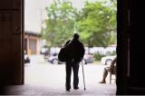 A man with a cane walks out of a door
