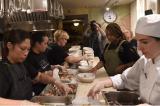 Restaurant workers gather around a table and plate food