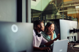 Programmers working together on a computer in office discussing a project - stock photo