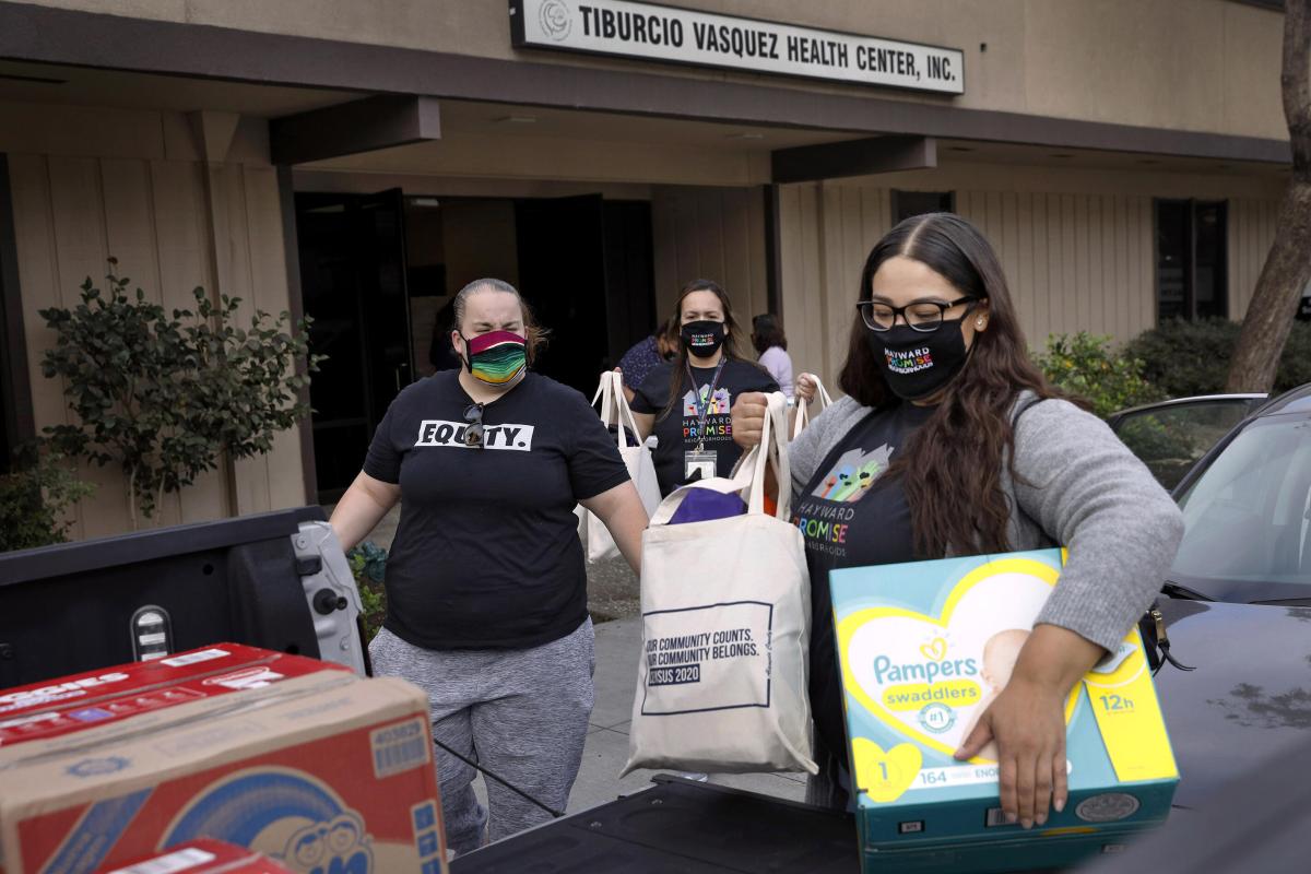 Roxana Cruz with Hayward Promise Neighborhoods (in the black mask) and other volunteers and staff load up cars with essential items